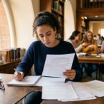 Studentka socjologii nad rozdziałem cel pracy w sali seminaryjnej
